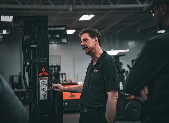 Trainer Russ pointing at a guide on a forklift mast